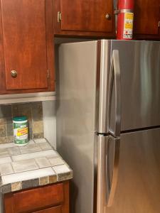 a stainless steel refrigerator in a kitchen with wooden cabinets at Cozy House of the South Overnight Guesthouse Rentals in Monroe