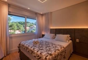 a bedroom with a bed with a large window at Locar-in Canela Bellagio - Infraestrutura Completa in Canela +43 photos