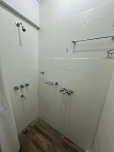 a white bathroom with a shower with a wooden floor at Departamento en el corazón de Tartagal in Tartagal +3 photos