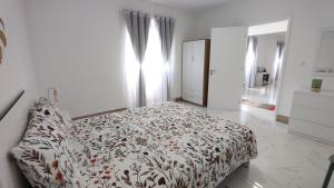 a white bedroom with a bed with a floral bedspread at Azure Vista Lodge in Nordestinho