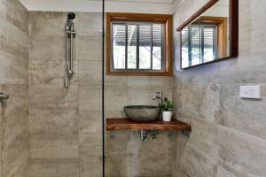 Un baño con ducha de cristal con lavabo. en Macs Beach Bungalow, en Macmasters Beach