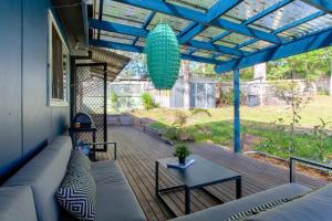 Un patio con un sofá y una mesa en un porche. en Macs Beach Bungalow, en Macmasters Beach