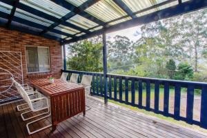 Un patio con una mesa y sillas en una terraza. en Macs Beach Bungalow, en Macmasters Beach