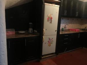 a white refrigerator in a kitchen with black cabinets at Maison Duplex pied dans l'eau in Cabo Negro