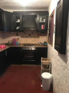 a kitchen with black cabinets and a toilet at Maison Duplex pied dans l'eau in Cabo Negro