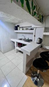 a white kitchen with a sink and a stool at Apartamento Barranquero Centro in Quimbaya +6 photos