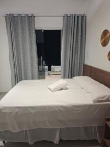 a bedroom with a large white bed with a window at Pousada Chalés da Serra in Cuité +15 photos