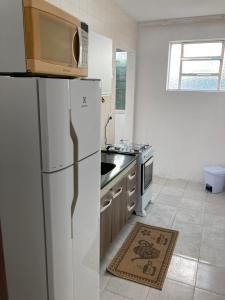 a kitchen with a white refrigerator and a stove at Apartamento aconchegante in Rio Grande