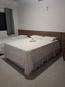 a bedroom with a large bed with white sheets at Pousada Chalés da Serra in Cuité