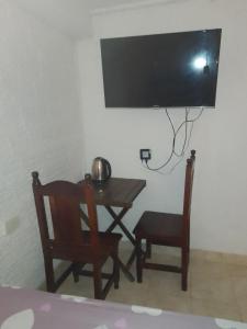 a room with a table and chairs and a television on a wall at Hostel Trinidad in San Salvador de Jujuy