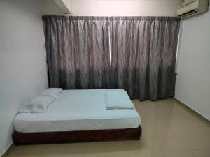 a bedroom with a bed and a window with a curtain at Travellers Space 2 in Kuantan
