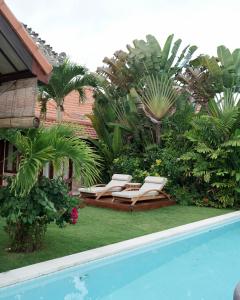 een paar ligstoelen naast een zwembad bij Tropical Villa Asmara - 400sqm Garden Oasis with large Pool and Scenic Views in Uluwatu