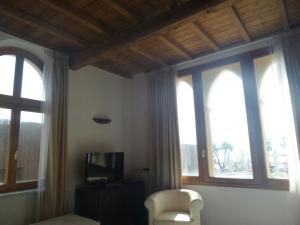 a room with two windows and a chair and a television at Cala Dei Mori in Livorno