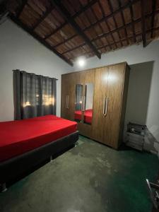 a bedroom with a red bed and wooden cabinets at Cantinho da Herança in Pirenópolis +15 photos