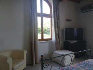 a bedroom with a tv and a chair and a window at Cala Dei Mori in Livorno