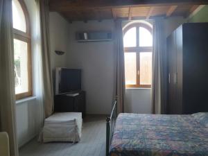 a bedroom with a bed and a tv and two windows at Cala Dei Mori in Livorno