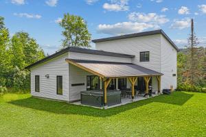 a white house with a porch with a deck at Chalet MoCo in Saint Come