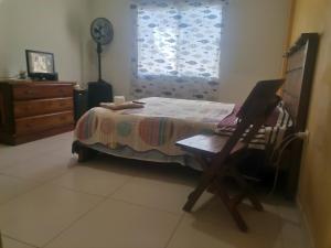 a bedroom with a bed and a laptop on a chair at Habitación con baño privado mas servicio de taxi aeropuerto in Santa Cruz de la Sierra