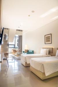 a hotel room with two beds and a living room at Skysuites Residence Surabaya in Kedungbaruk +42 photos