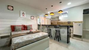 ein kleines Schlafzimmer mit einem Bett und einer Küche in der Unterkunft The Férias | Suites Praia in Cabo Frio