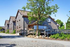 une maison en bois avec un arbre en face de celle-ci dans l'établissement Ferienhäuser im Torfhaus Harzresort, Torfhaus, à Torfhaus