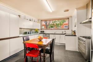 a kitchen with white cabinets and a wooden table and chairs at Art House in Melbourne