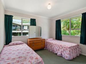 a bedroom with two beds and a dresser and windows at Kinloch Family Retreat - Kinloch Holiday Home in Kinloch