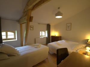 ein Schlafzimmer mit zwei Betten und einem Tisch und zwei Fenstern in der Unterkunft Charmant domaine avec 2 gîtes pour 15 pers, animaux admis, wifi, jardin et terrasse - FR-1-496-368 in Les Salles