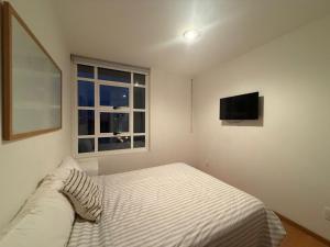 Un dormitorio con una cama y un televisor en la pared. en Frida my Loft, en Ciudad de México