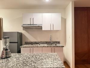 Una cocina con gabinetes blancos y encimera. en Frida my Loft, en Ciudad de México 7 fotos más