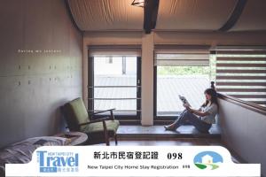 a woman sitting on a window sill reading a book at Taipei Jinguashi Cloud Mountain Homestay B&B in Jiufen