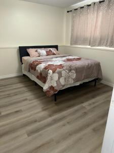 a bedroom with a bed and a wooden floor at Joyful Home Regina in Regina
