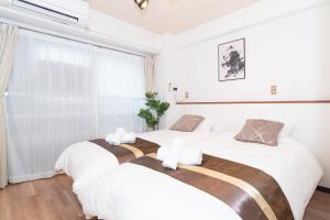 神户Stay Kobe B的卧室设有两张床,拥有白色的墙壁和窗户。