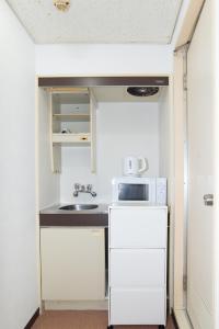 a small kitchen with a sink and a refrigerator at Stay KobeB in Kobe