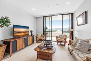 a living room with a couch and a tv at Boutique City Apartment in Coffs Harbour