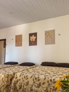 a bedroom with two beds and three paintings on the wall at Casasukyara in Amontada
