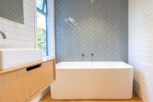 a bathroom with a tub and a sink at Kiwi Street Retreat in Waiheke Island