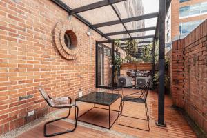 a patio with a table and chairs on a brick wall at Soy Local Parque La 93 in Bogotá