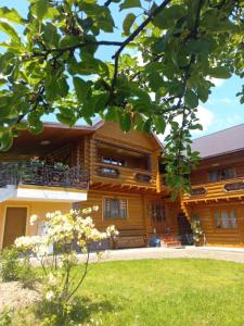 a wooden house with a lawn in front of it at Sadyba Medova nasoloda in Guta