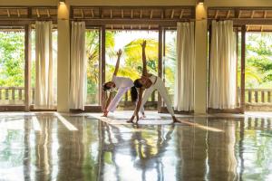 2 femmes faisant une pose de yoga dans une chambre dans l'établissement Puri Gangga Resort Ubud, à Tegalalang