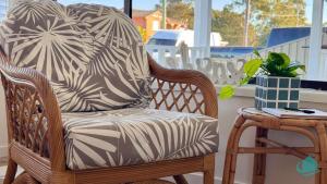 a wooden rocking chair with a pillow on a table at Barefoot at Blacksmiths Beach in Blacksmiths