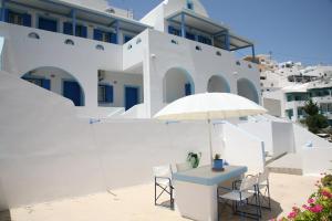 a table and chairs with an umbrella in front of a building at Panselinos in Anafi