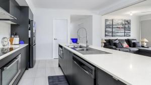 een keuken met een spoelbak en een woonkamer bij Relax Poolside By The Canal in Bongaree