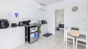 een keuken met witte kasten en een aanrechtblad bij Relax Poolside By The Canal in Bongaree +11 foto's