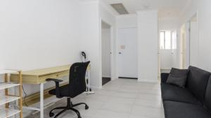 een woonkamer met een bureau en een bank bij Relax Poolside By The Canal in Bongaree