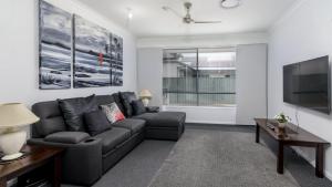 een woonkamer met een bank en een flatscreen-tv bij Relax Poolside By The Canal in Bongaree