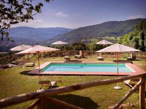 a swimming pool with umbrellas and chairs with mountains in the background at Villa in Tuscany with Heated Pool & Sports Court in Poppi