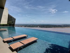 una piscina con 2 bancos en la parte superior de un edificio en The Peak Residence Service Apt By Hayden, en Phnom Penh