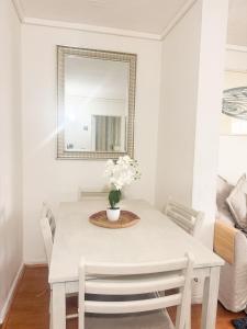 a white dining room table with a vase of flowers on it at Departamento Reñaca in Viña del Mar +25 photos
