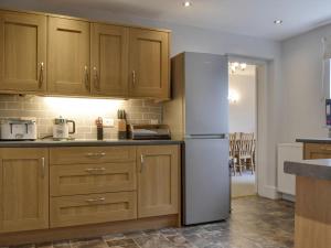 a kitchen with wooden cabinets and a white refrigerator at The Birches in Keswick